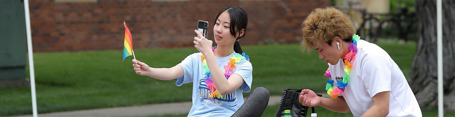 a student takes a picture of a pride flag at a pride month celebration event